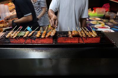 Midsection of man preparing food on barbecue grill