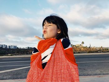 Girl with wrapped in towel on road against cloudy sky