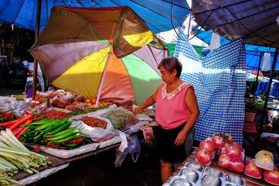 Woman with vegetables for sale at market stall