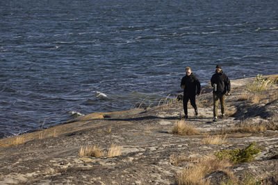 View of men walking at rocky coast