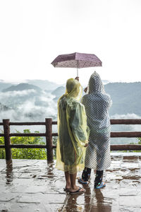 Rear view of woman with umbrella standing on rainy day