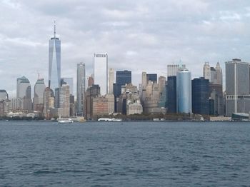 Sea by modern buildings against sky in city