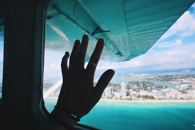 Cropped hand on window of airplane