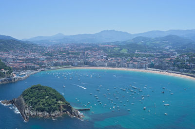 Aerial view of cityscape and mountains against clear blue sky