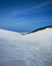 Snow covered land against blue sky