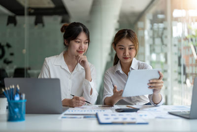 Businesswoman using mobile phone while sitting on table