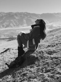 Man sitting on land against sky