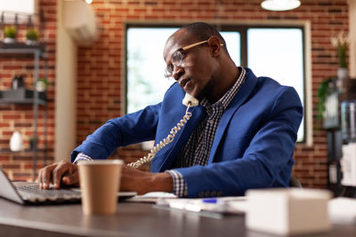 Young man using mobile phone while sitting at table