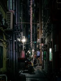 Illuminated street amidst buildings in city at night