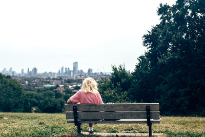 Rear view of woman sitting on bench at park