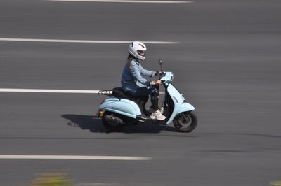 Man riding motor scooter on road