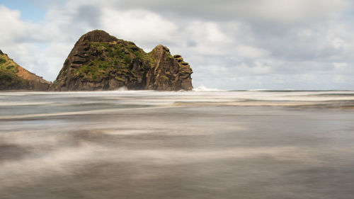 Rock formation on beach against sky