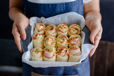 Midsection of woman holding food in baking sheet