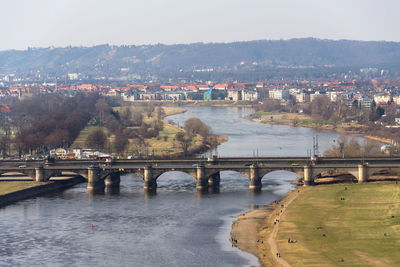 Bridge over river by buildings in city against sky