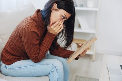 Young woman using mobile phone while sitting at home