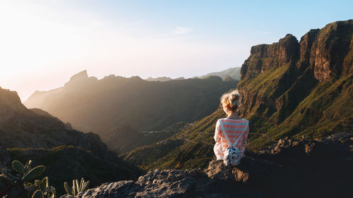 Rear view of woman standing on mountain against sky