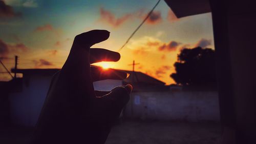 Close-up of silhouette hand against sunset sky