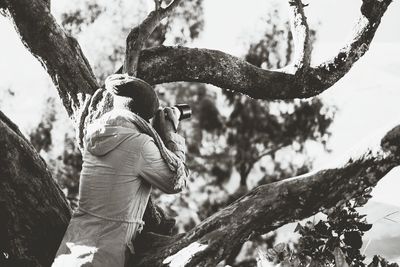 Side view of man on tree trunk during winter