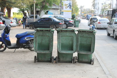 Garbage bins in parking lot by road at city