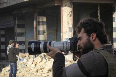 Side view of man photographing in war zone