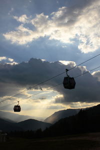 Overhead cable cars over mountains against sky during sunset