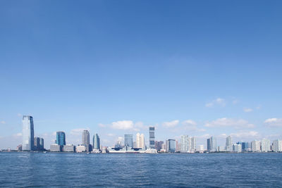 Sea by cityscape against clear sky