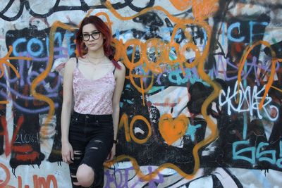 Young woman standing against graffiti wall