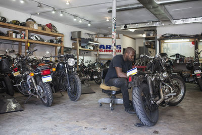 A young man fixing a motorcycle.