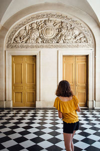 Rear view of woman standing against door