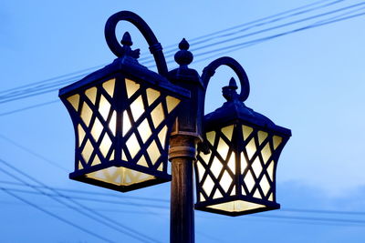 Low angle view of illuminated street light against blue sky