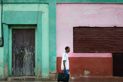 Side view of man standing against building