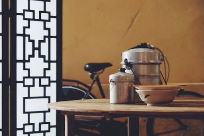 Close-up of containers on table and bicycle against wall