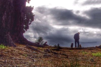 Man standing on grassy field against cloudy sky