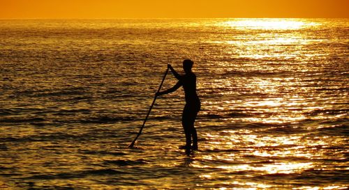 Silhouette of people in sea at sunset