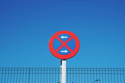 Low angle view of road sign against clear blue sky