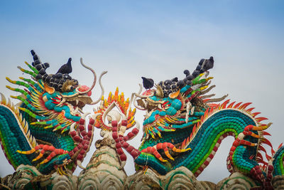 Low angle view of statue against sky at temple