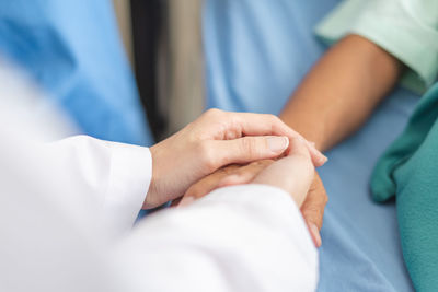 Cropped image of female doctor holding hand of patient at hospital 