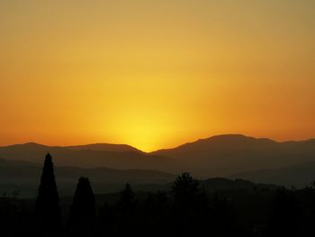 Scenic view of silhouette mountains against orange sky