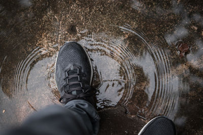 Low section of man in shoes standing on puddle