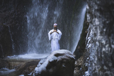Full length of man standing on rock in forest