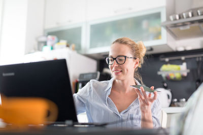 Business woman using smart phone while sitting at home