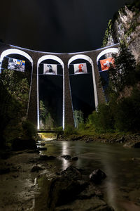 Arch bridge over river at night