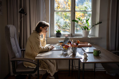 Pensive teenager reading text in laptop, studying online, working as freelancer, writer, tutor