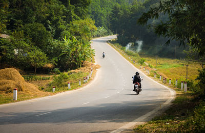 Rear view of woman riding motorcycle on road