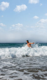 Man surfing in sea against sky