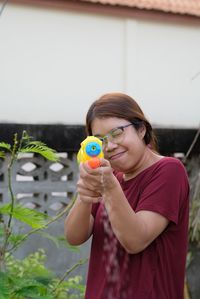 Portrait of woman holding eyeglasses while standing outdoors