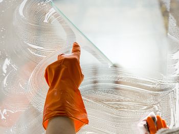 Cropped image of person cleaning glass