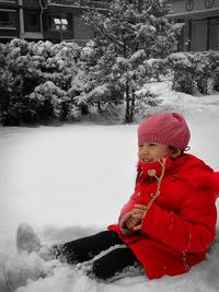 Close-up of child on snow covered tree during winter