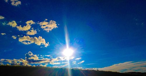 Low angle view of sunlight streaming through clouds