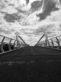 Low angle view of footbridge against cloudy sky